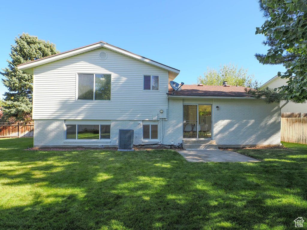 Back of property with central AC unit, a yard, and a patio area