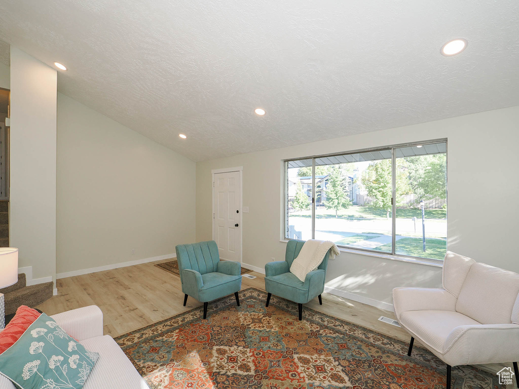 Living room with lofted ceiling, a textured ceiling, and hardwood / wood-style flooring