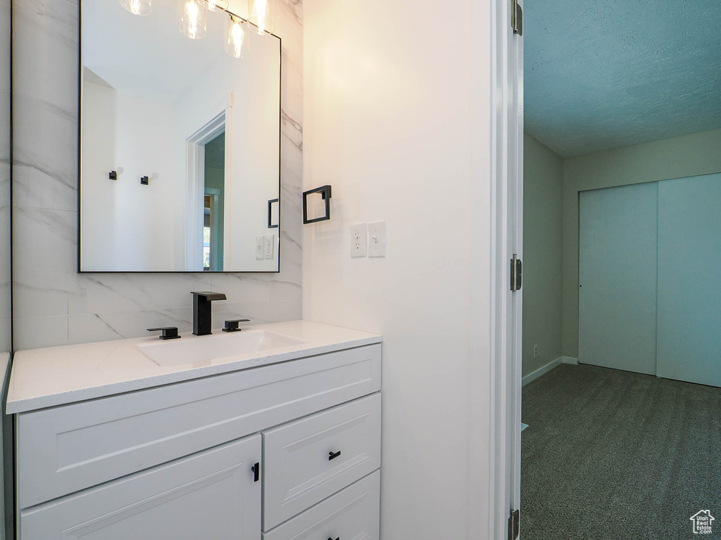 Bathroom with decorative backsplash, a textured ceiling, and vanity