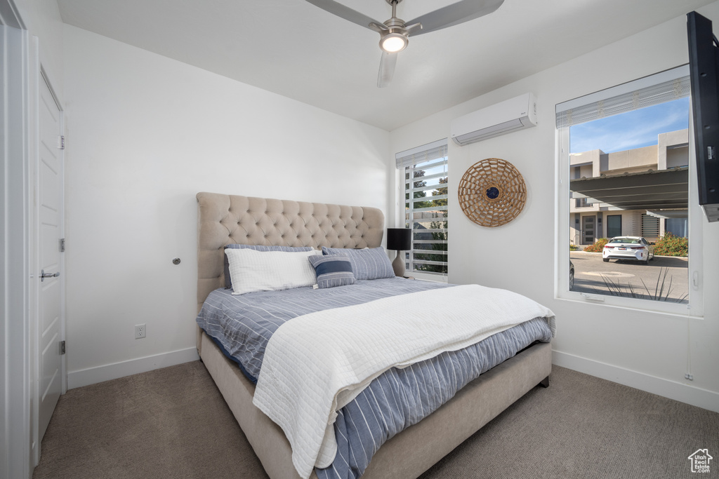 Bedroom with an AC wall unit, ceiling fan, and dark carpet