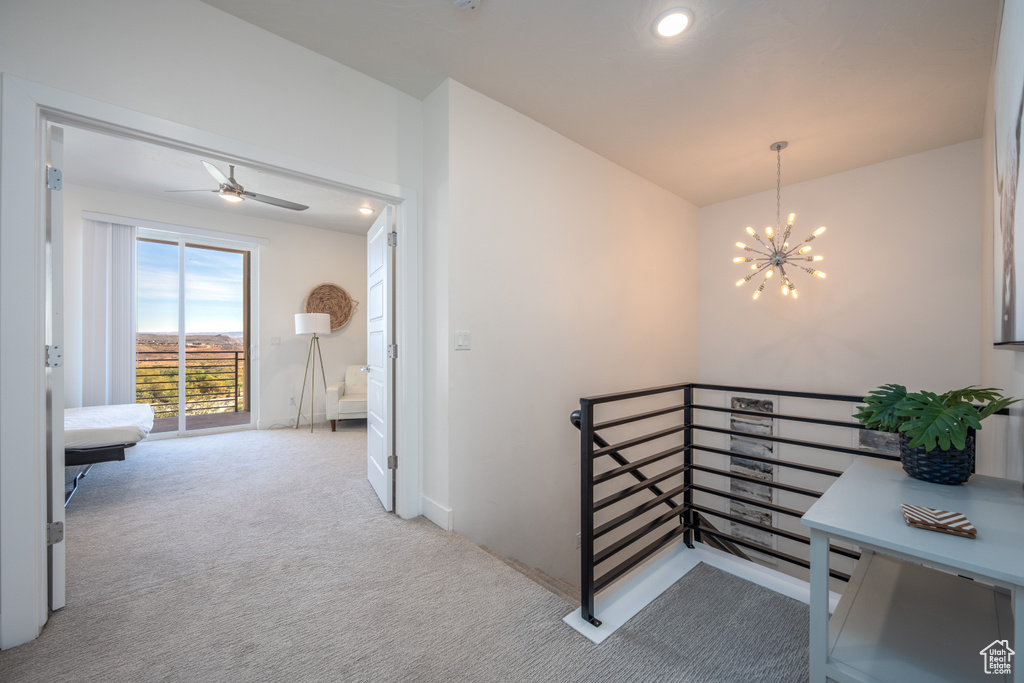 Hallway featuring a notable chandelier and light colored carpet