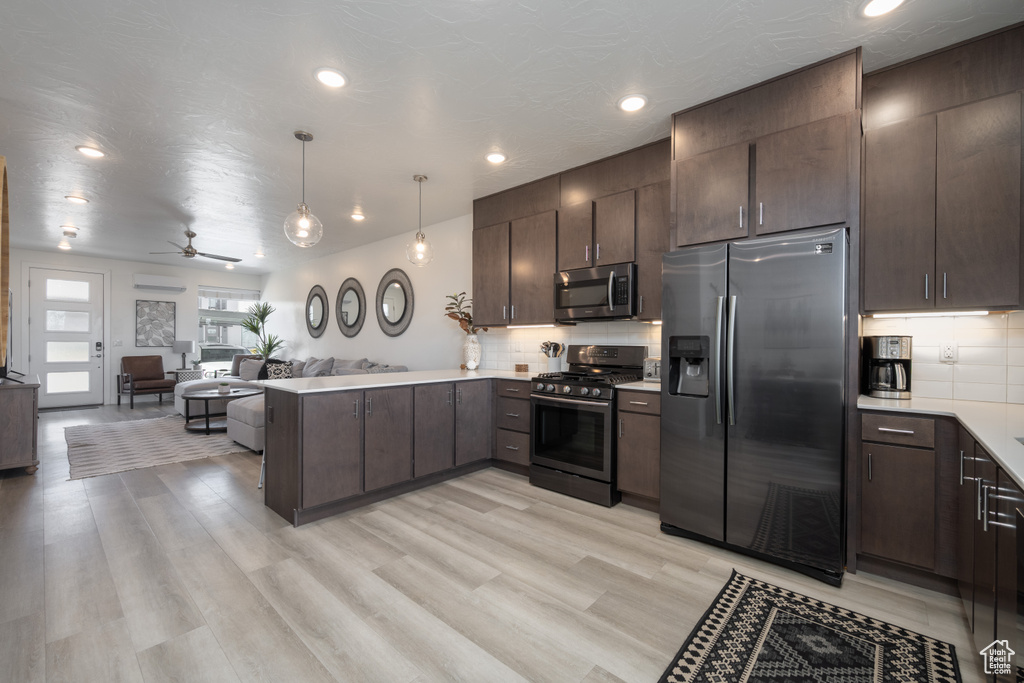 Kitchen featuring ceiling fan, pendant lighting, kitchen peninsula, appliances with stainless steel finishes, and light wood-type flooring