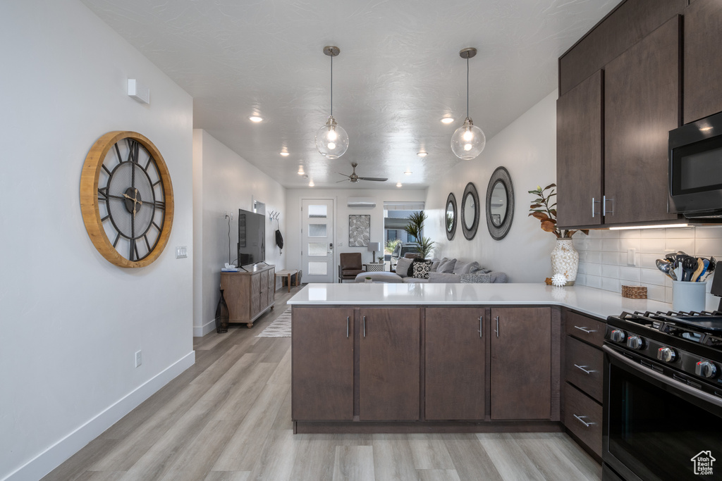 Kitchen with kitchen peninsula, light hardwood / wood-style flooring, stainless steel appliances, decorative light fixtures, and ceiling fan