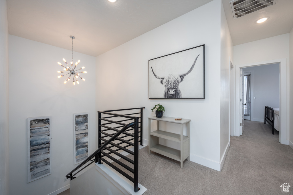 Hall featuring an inviting chandelier and light carpet