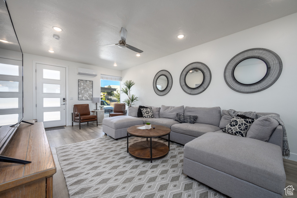 Living room featuring ceiling fan, light hardwood / wood-style floors, and a wall mounted AC