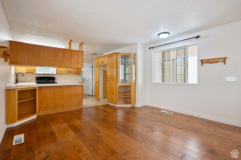 Kitchen with a textured ceiling, kitchen peninsula, dark hardwood / wood-style flooring, and sink