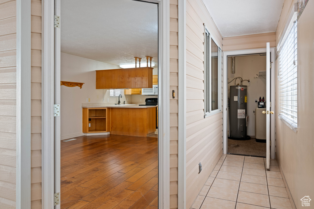 Hallway with sink, light hardwood / wood-style flooring, and electric water heater