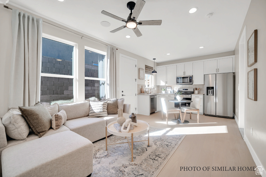 Living room with ceiling fan, sink, and light hardwood / wood-style floors