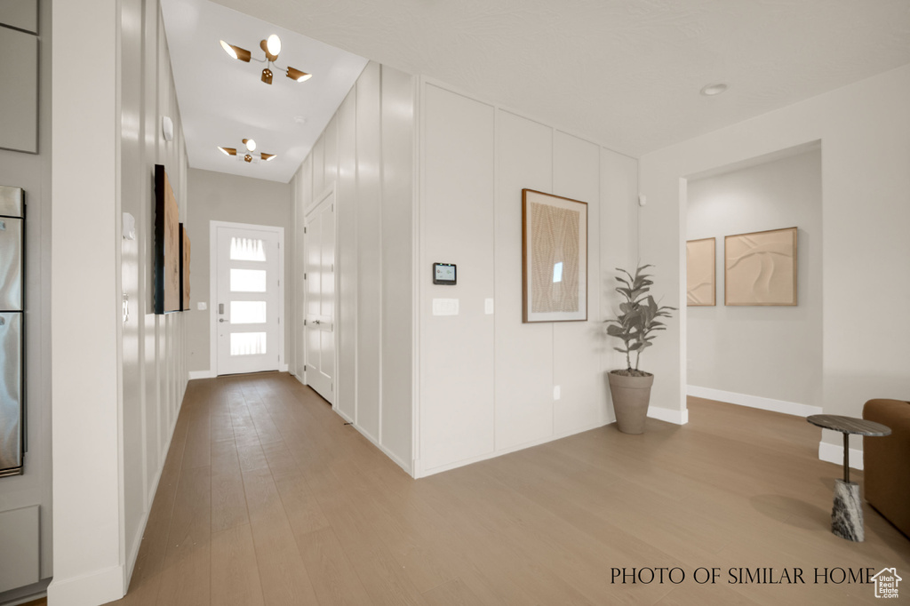 Hall with an inviting chandelier and light hardwood / wood-style flooring