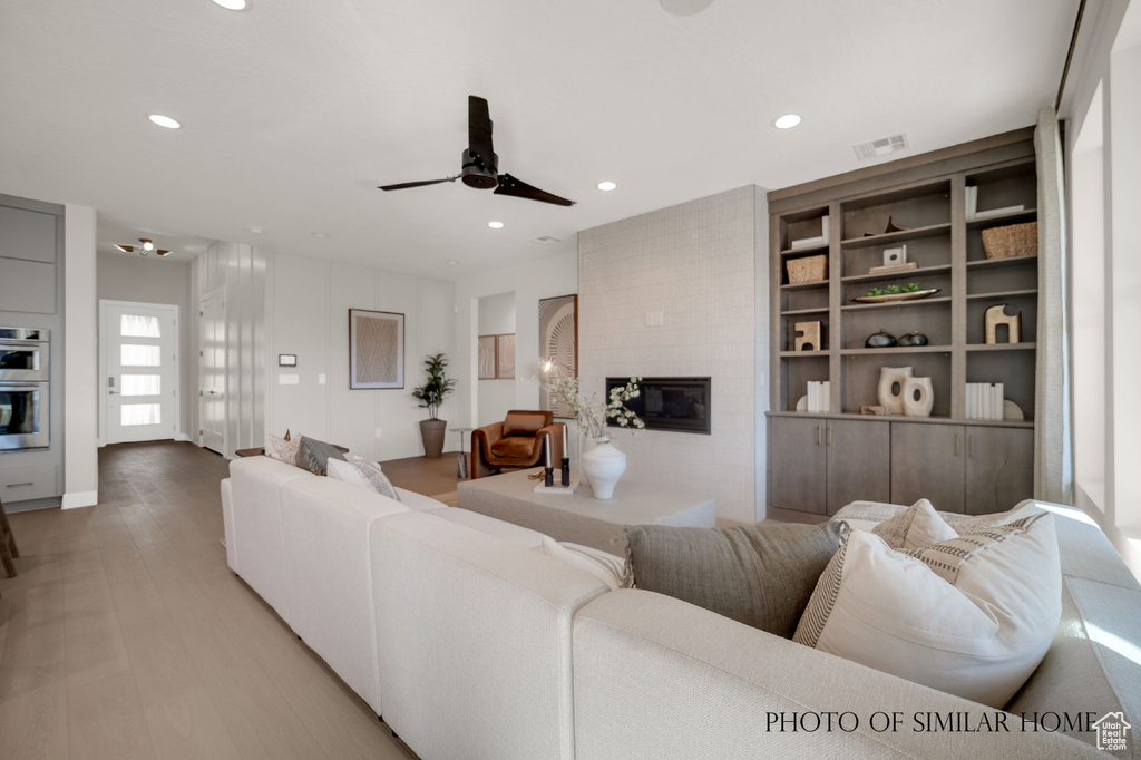 Living room featuring hardwood / wood-style floors, ceiling fan, and a fireplace