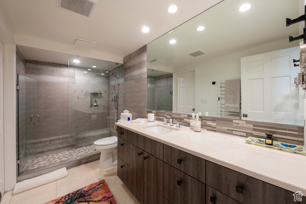 Bathroom featuring vanity, toilet, an enclosed shower, and tasteful backsplash