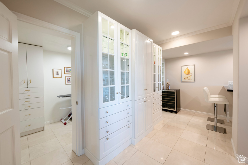 Bathroom with wine cooler, crown molding, and tile patterned flooring