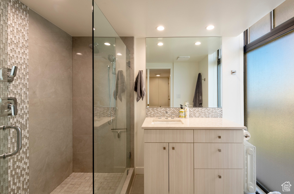 Bathroom with backsplash, vanity, and a shower with shower door