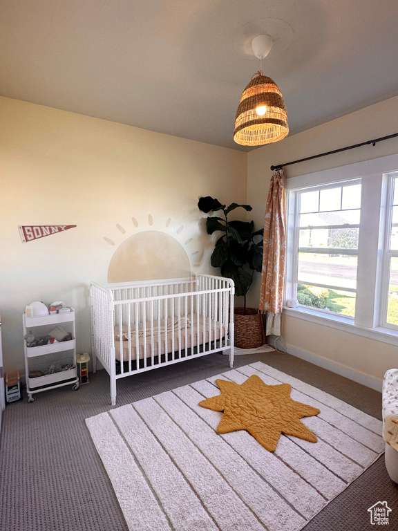 Bedroom featuring dark carpet and a nursery area