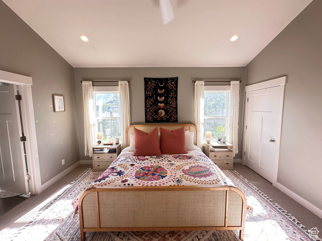 Carpeted bedroom with lofted ceiling and multiple windows