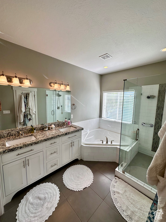 Bathroom with vanity, plus walk in shower, a textured ceiling, and tile patterned floors