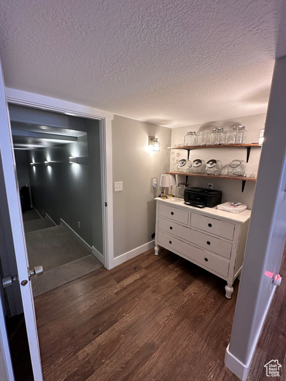 Corridor with a textured ceiling and dark hardwood / wood-style flooring