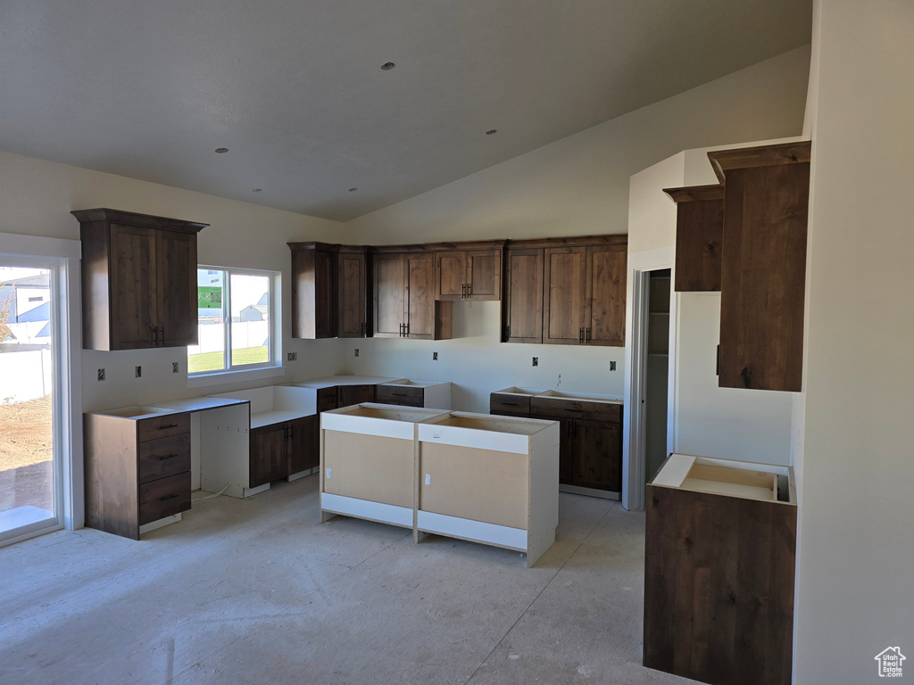 Kitchen featuring dark brown cabinets, lofted ceiling, and a healthy amount of sunlight