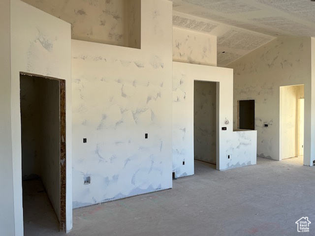 Spare room featuring concrete floors and lofted ceiling