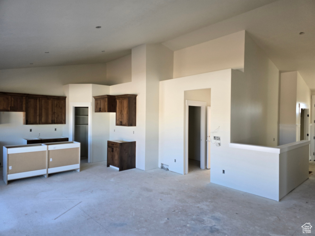 Kitchen featuring high vaulted ceiling, white refrigerator, and dark brown cabinetry