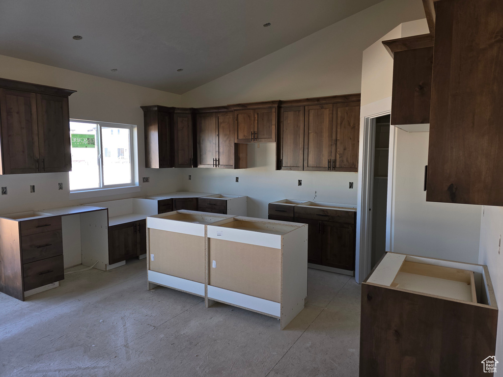 Kitchen featuring dark brown cabinetry, high vaulted ceiling, and a center island