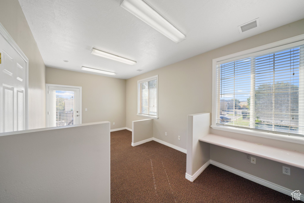 Empty room with dark carpet and a wealth of natural light