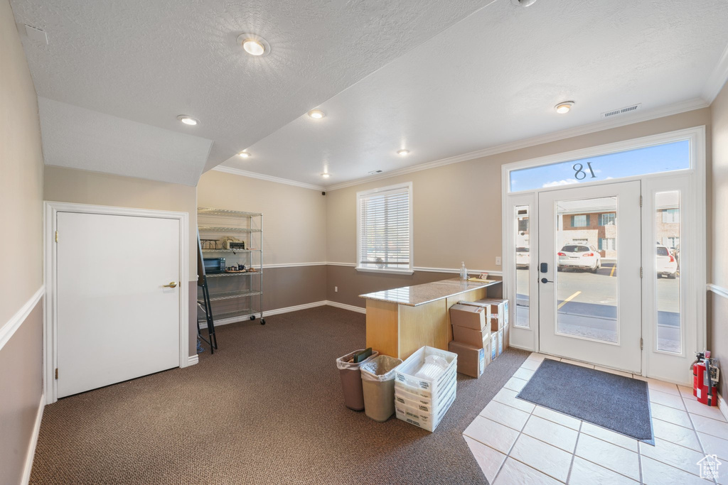 Carpeted foyer entrance with a textured ceiling and crown molding