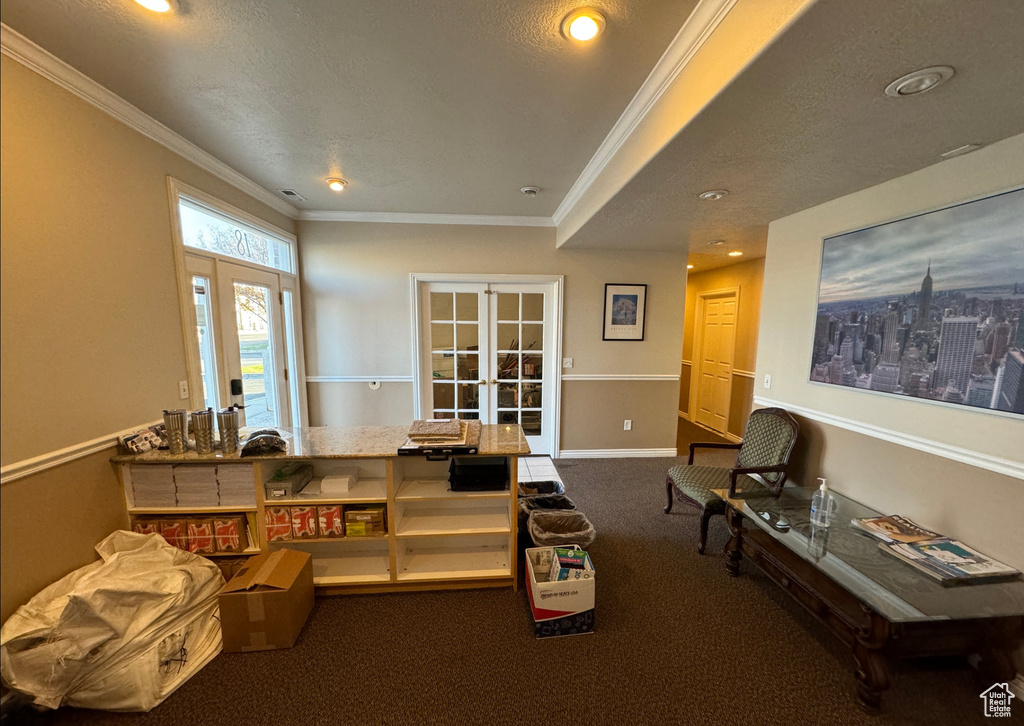 Interior space featuring ornamental molding, dark colored carpet, a textured ceiling, and french doors