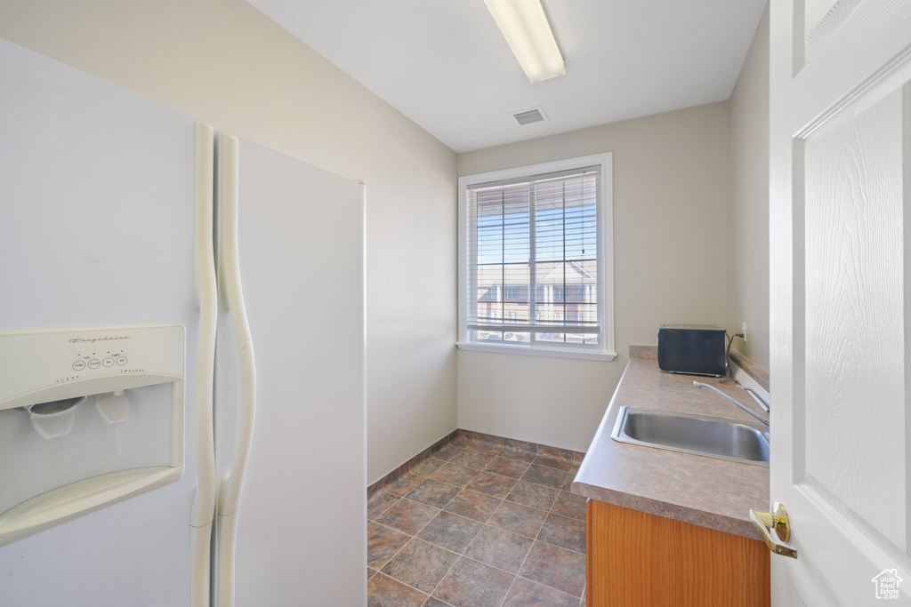 Interior space with white fridge with ice dispenser and sink