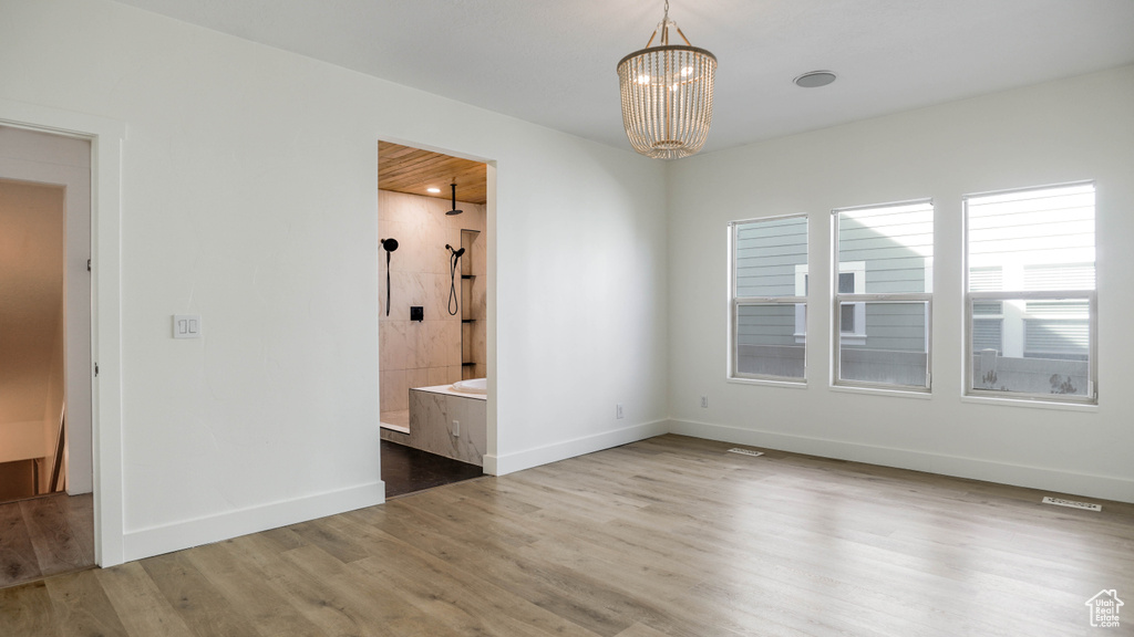 Unfurnished room with hardwood / wood-style flooring and a chandelier