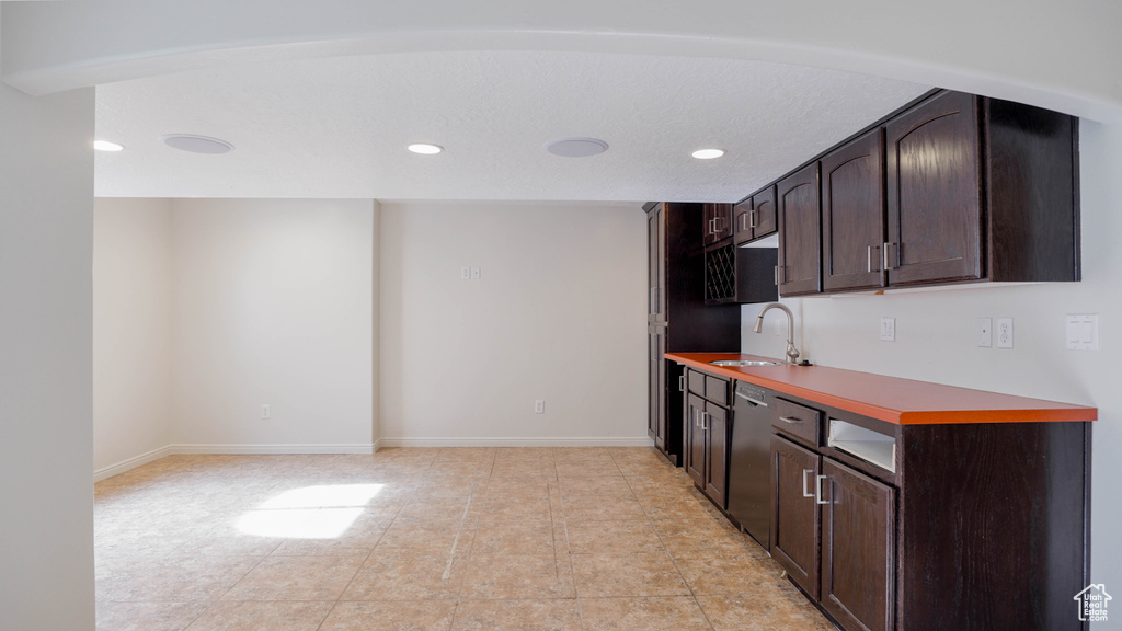 Bar with dark brown cabinetry, light tile patterned floors, sink, and stainless steel dishwasher