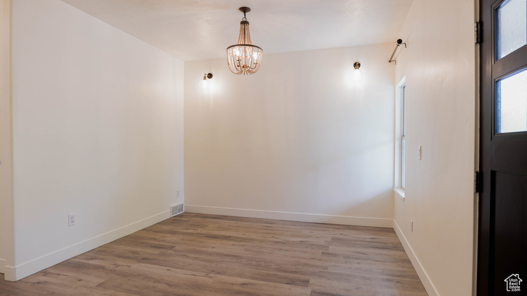 Spare room with light hardwood / wood-style floors and an inviting chandelier