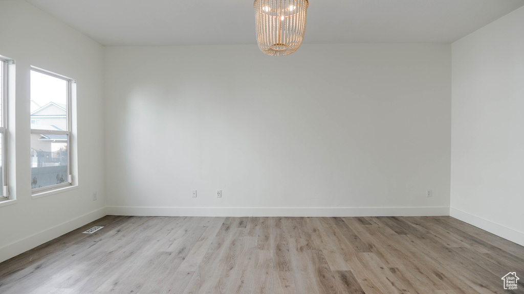 Empty room featuring a notable chandelier and light hardwood / wood-style floors