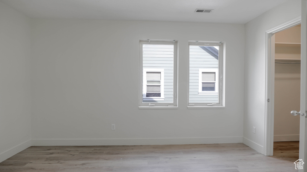 Unfurnished bedroom featuring a spacious closet, a closet, and light hardwood / wood-style floors