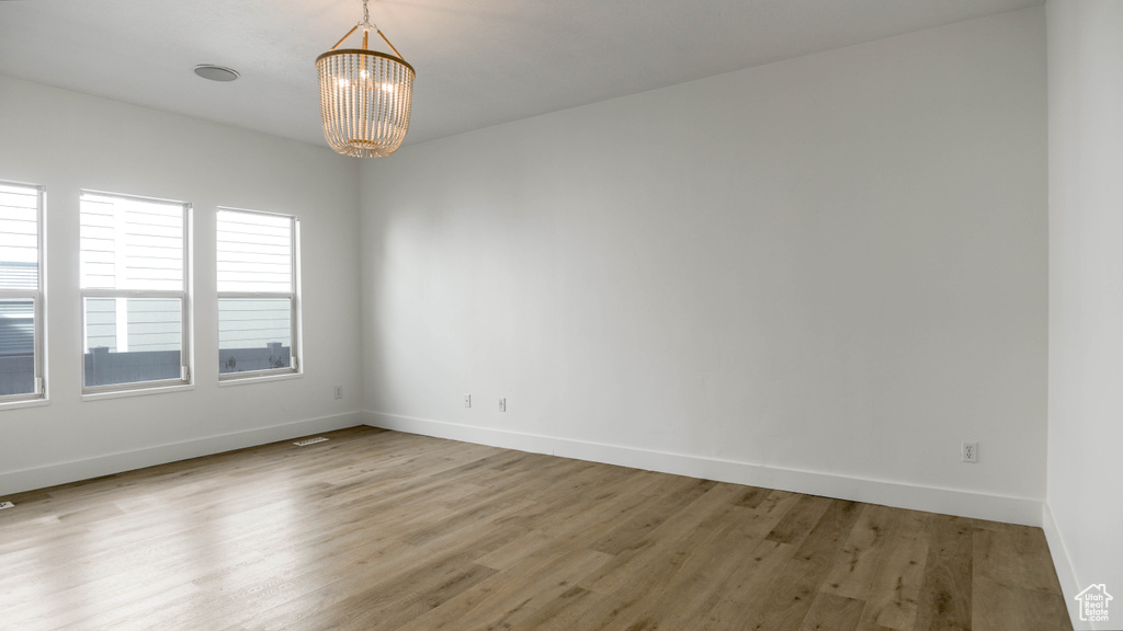 Spare room with an inviting chandelier and wood-type flooring