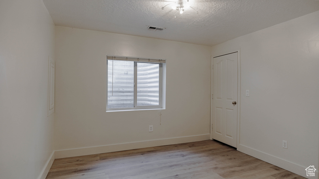 Spare room featuring light wood-type flooring and a textured ceiling