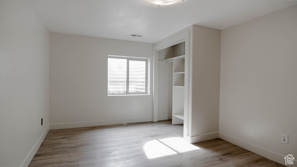 Unfurnished bedroom with light hardwood / wood-style flooring and a closet