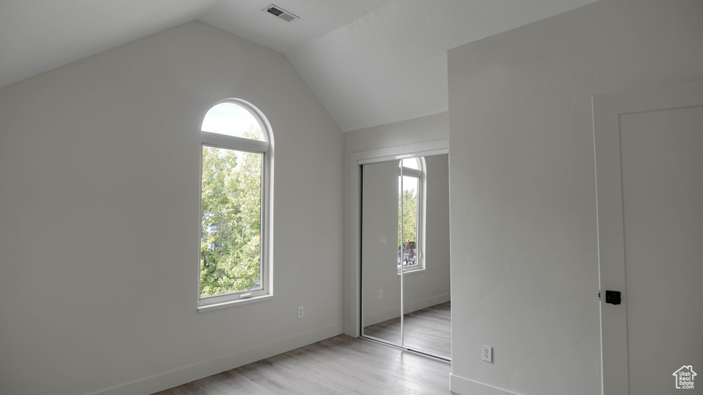 Unfurnished room featuring light hardwood / wood-style flooring, vaulted ceiling, and a healthy amount of sunlight