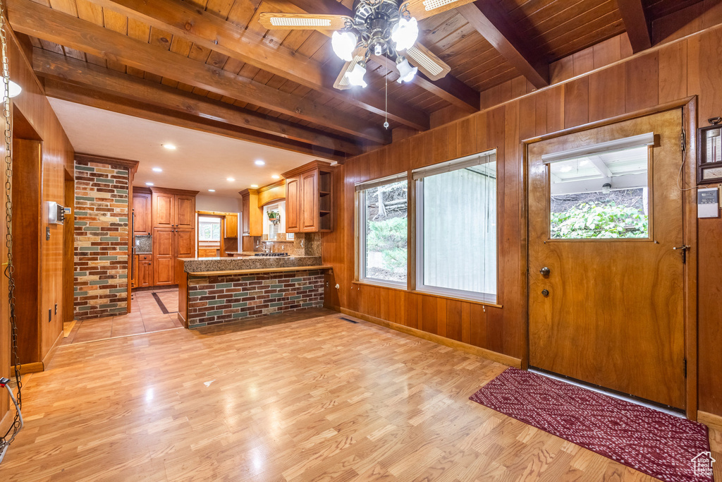 Foyer featuring ceiling fan, beam ceiling, wooden walls, wooden ceiling, and light hardwood / wood-style floors