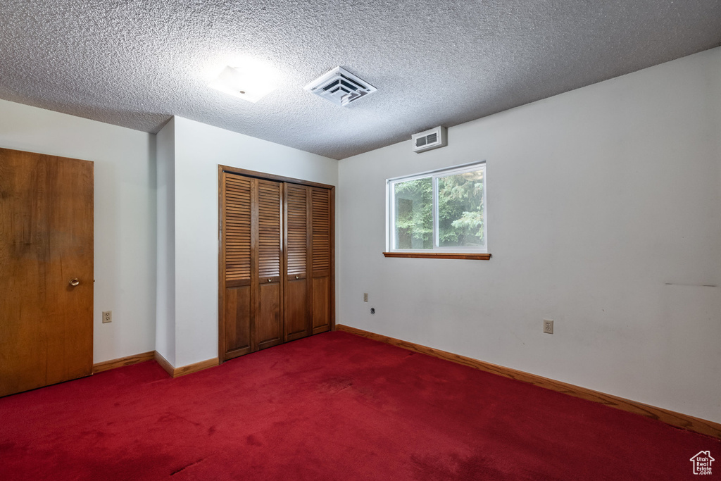 Unfurnished bedroom with carpet, a closet, and a textured ceiling