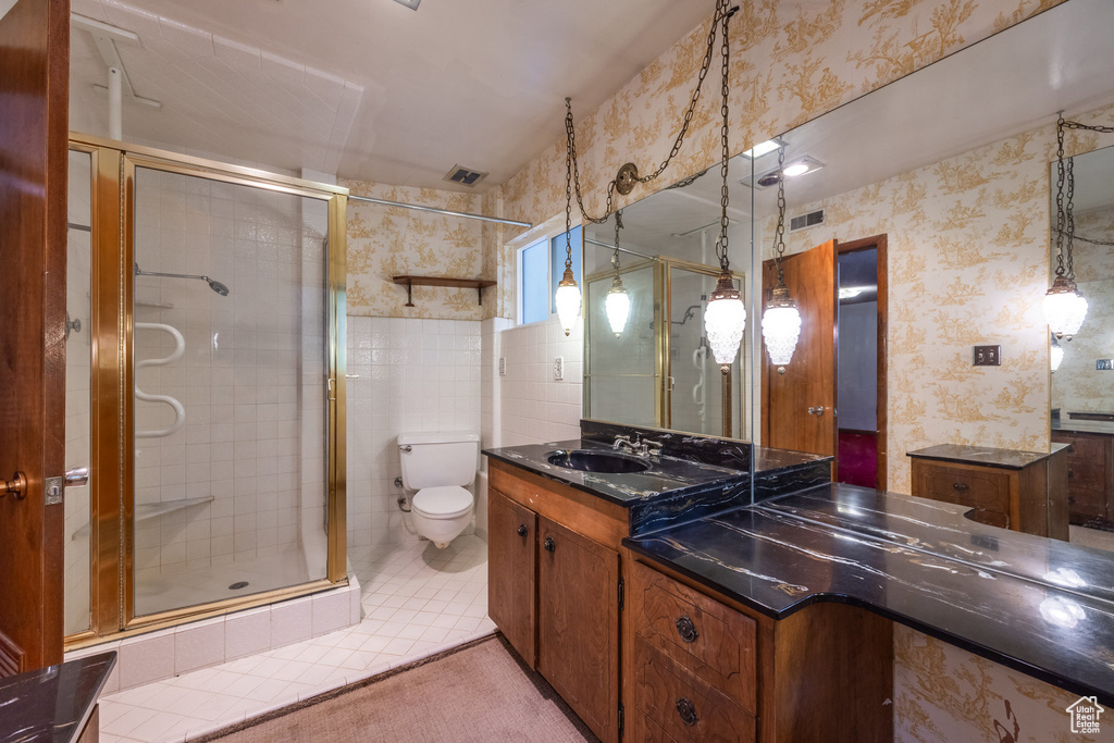 Bathroom featuring tile patterned flooring, walk in shower, vanity, and toilet