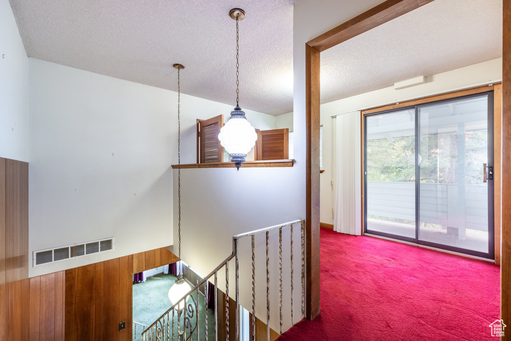 Hallway with carpet floors, a textured ceiling, and vaulted ceiling