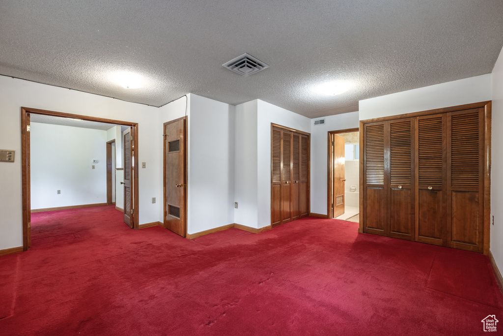 Unfurnished bedroom featuring a textured ceiling, carpet, and ensuite bathroom