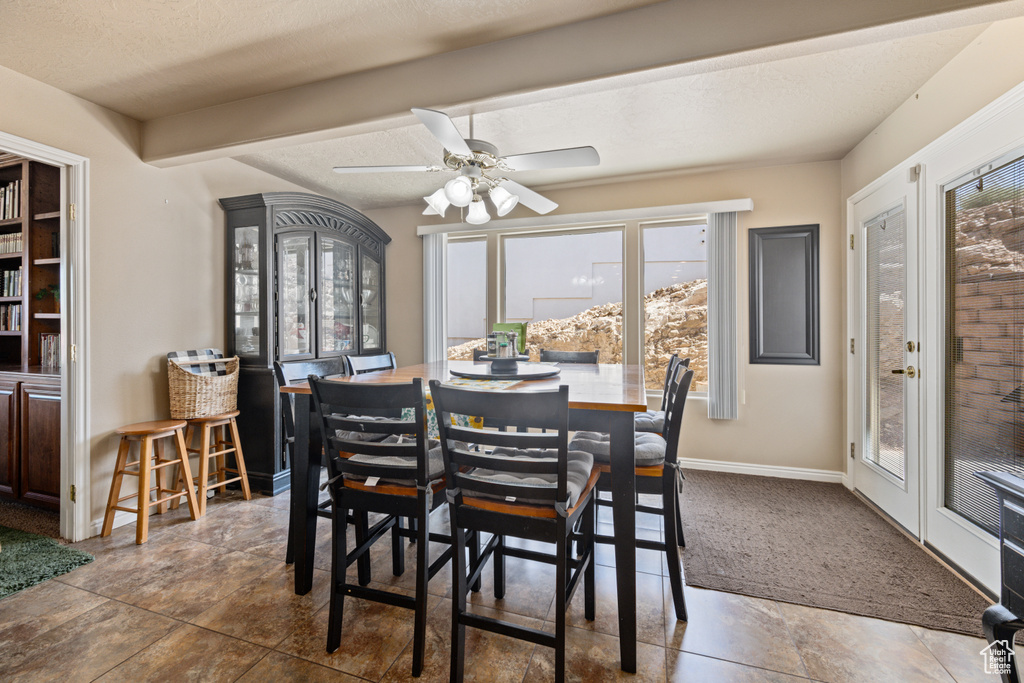 Dining area with dark tile patterned floors, ceiling fan, and a textured ceiling