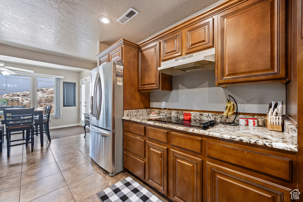 Kitchen with ceiling fan, light tile patterned flooring, stainless steel fridge, a textured ceiling, and black electric cooktop