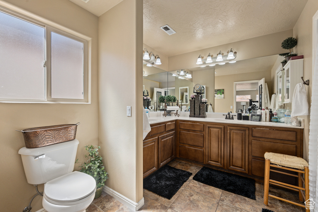 Bathroom featuring a textured ceiling, vanity, and toilet