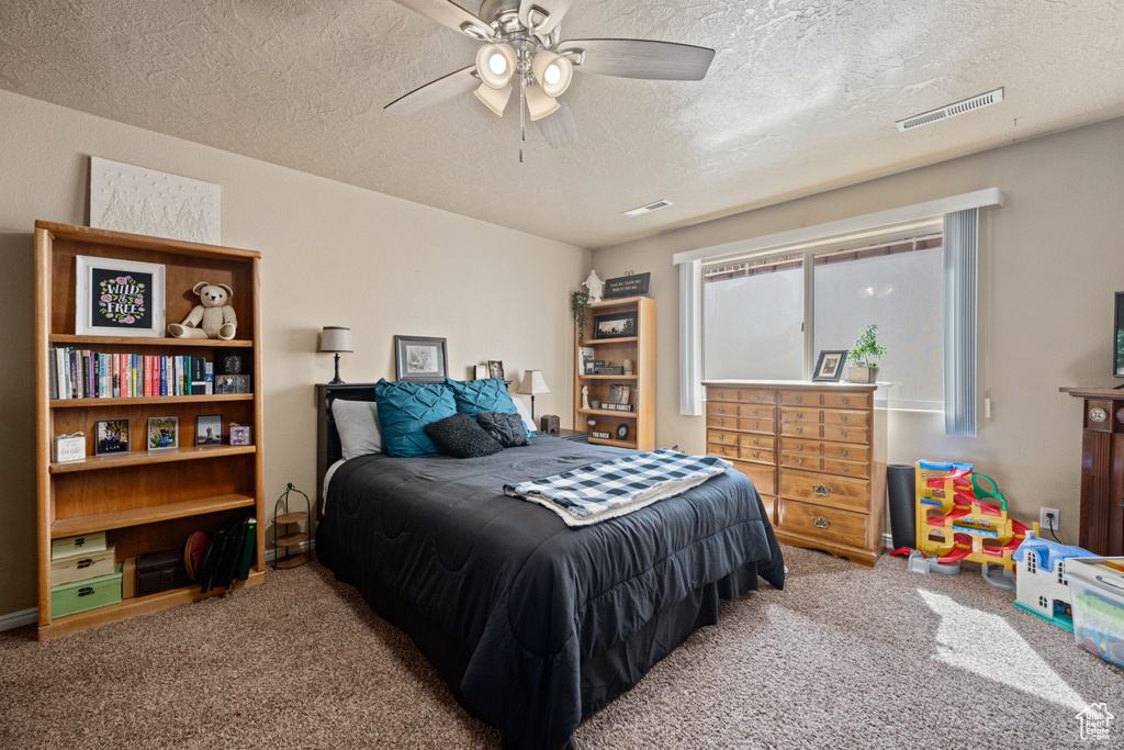 Carpeted bedroom featuring ceiling fan and a textured ceiling