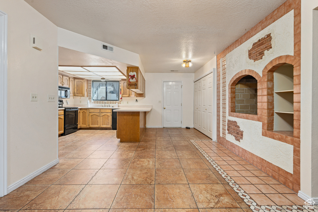 Kitchen with a textured ceiling, black appliances, and light tile patterned flooring