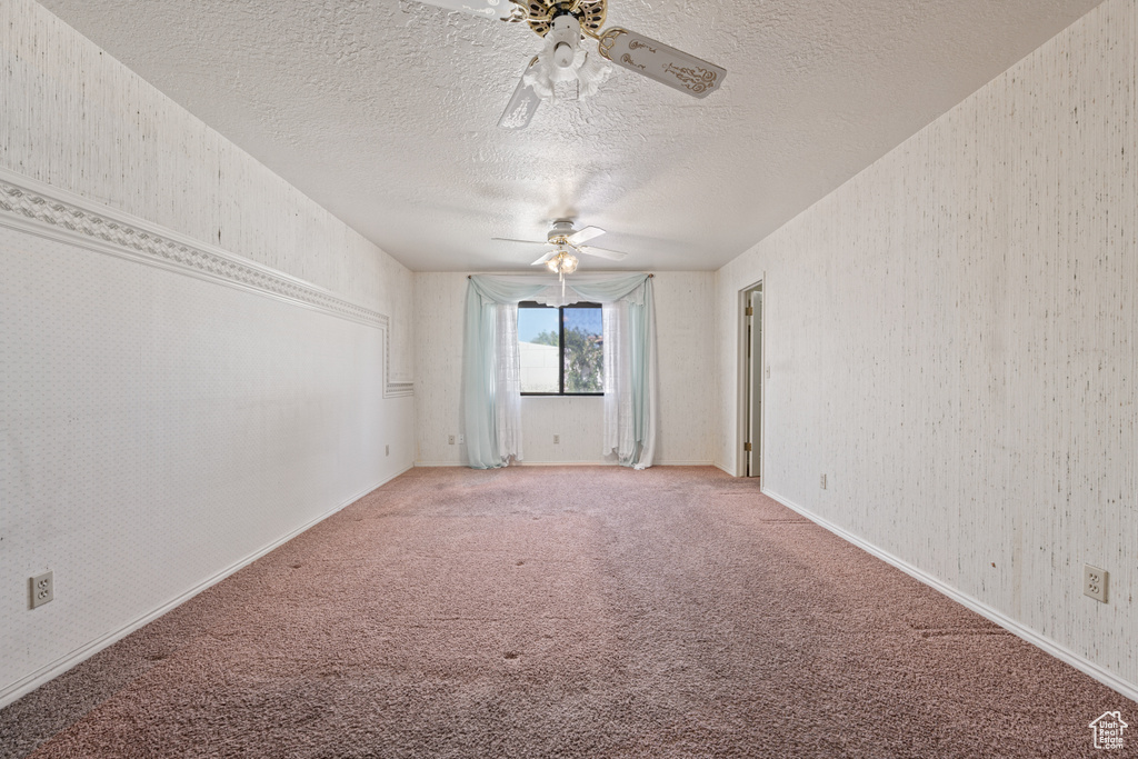 Unfurnished room featuring ceiling fan, carpet floors, and a textured ceiling