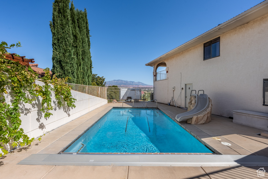 View of swimming pool with a water slide, a mountain view, and a patio area